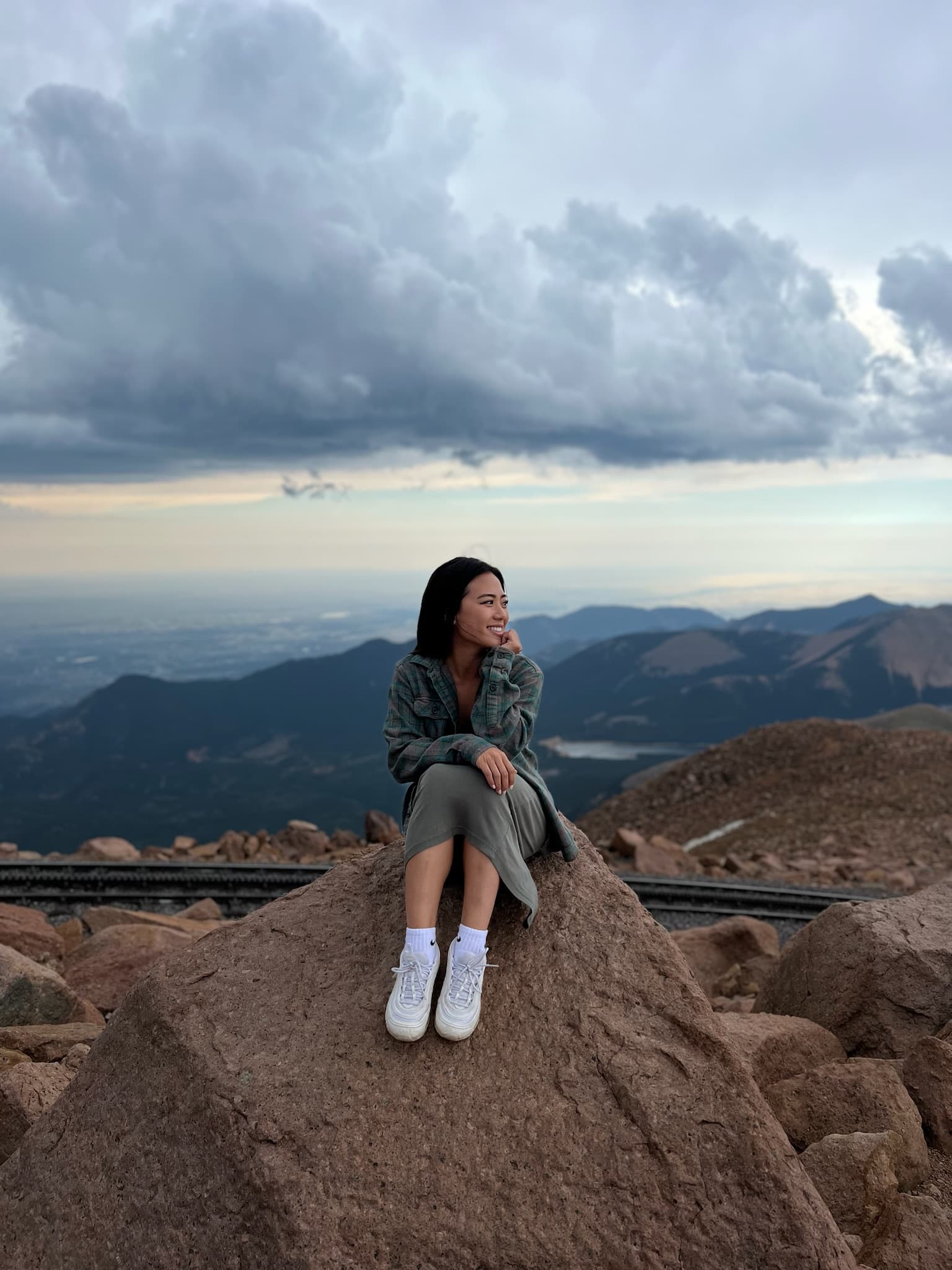 Jenny sitting on a rock high above the mountains